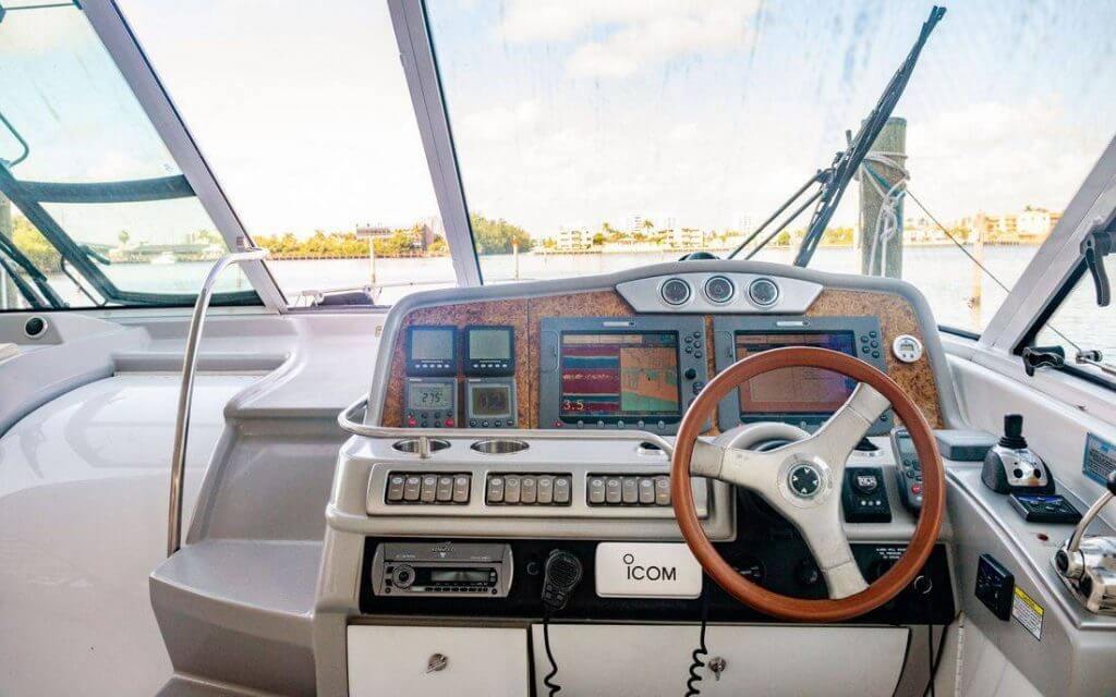 Helm of a 48′ Formula Cruiser with dual chartplotters and wood wheel, looking out over Biscayne Bay through the windshield